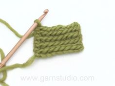 a green crochet with a wooden knitting needle