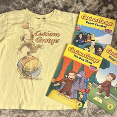 three children's books and t - shirt laying on the floor