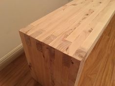 a wooden bench sitting on top of a hard wood floor next to a white wall