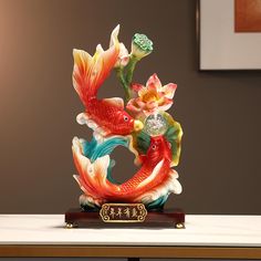 a statue of two fish and flowers on a table