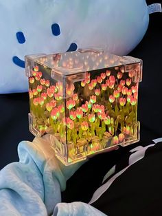 a clear box filled with flowers sitting on top of a table next to a stuffed animal