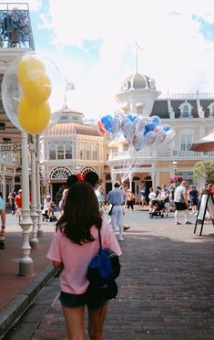 a girl is walking down the street with balloons