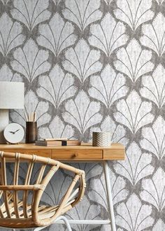 a desk with a chair, clock and lamp on it next to a wall paper