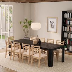 a dining room table and chairs with bookshelves in the background on an area rug