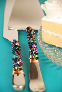 there are two silverware with colorful beads on them next to a piece of cake