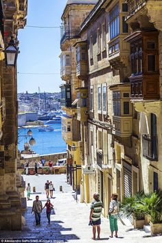 people are walking down an alley way near the water