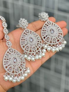 Statement Detailed Earrings with Matching Tikka. White Bead Contrast In Silver Finish Statement Accessory Item to bling up any outfit to wear at any special occasion Wedding Silver Chandbalis With Intricate Design, White Hand Set Bridal Earrings For Party, Hand Set White Bridal Earrings For Party, Bridal Earrings For Wedding And Eid, Bridal Earrings With Stone Work For Wedding Eid, Bridal Earrings With Stone Work For Wedding At Eid, Stone Work Bridal Earrings For Eid Wedding, Silver Jhumkas With Stone Work For Reception, Stone Work Bridal Earrings For Wedding And Eid