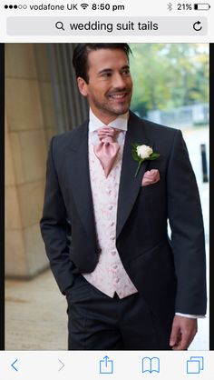 a man in a tuxedo smiles at the camera while wearing a pink bow tie