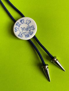 two blue and white necklaces sitting on top of a green surface