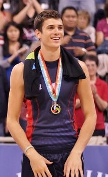 a young man standing on top of a basketball court holding a medal around his neck