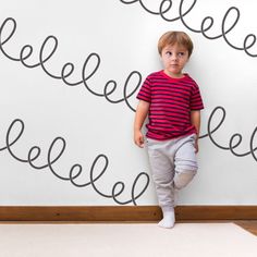 a little boy standing in front of a wall with writing on it