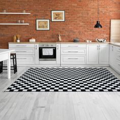 a black and white checkered rug in the middle of a kitchen with brick walls