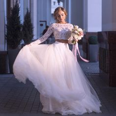 a woman in a white wedding dress is walking down the street with her hands on her hips