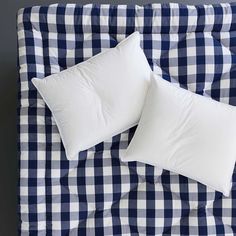 two white pillows sitting on top of a blue and white checkered bedspread