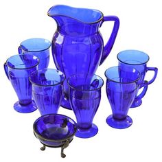 a blue glass pitcher and six glasses