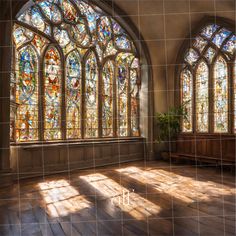 an empty room with stained glass windows and wooden flooring in front of the window