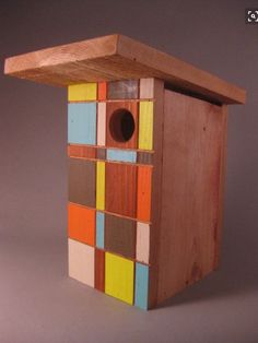 a bird house made out of wood with multicolored squares on the outside and inside