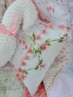 a white teddy bear laying on top of a bed next to pillows and a stuffed animal