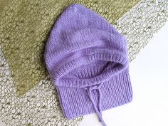 a purple knitted hat laying on top of a lace doily