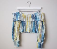 a crocheted top hanging on a hanger with clothes pins attached to it