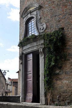 an old building with vines growing on the outside and door to another building in the background