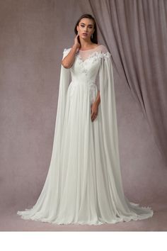 a woman in a white wedding gown and cape