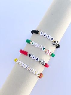 four bracelets with different colored beads and charms on each bead are displayed in front of a white background