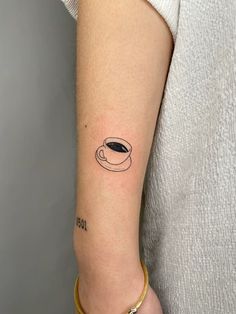 a woman's arm with a small coffee cup tattoo on the left inner arm