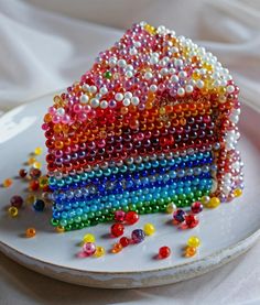 a white plate topped with a slice of cake covered in multicolored beads