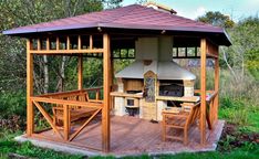 a wooden gazebo with an outdoor grill and picnic table in the middle of it