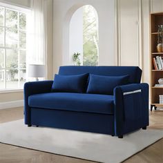 a blue couch sitting on top of a white rug next to a book shelf filled with books