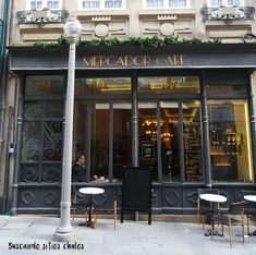 the entrance to a restaurant with tables and chairs in front of it, next to a lamp post