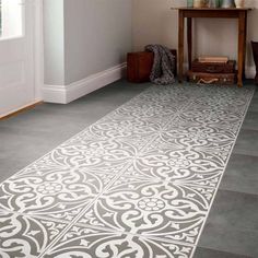 a white and grey rug in the corner of a room next to a table with vases on it