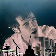 a man sitting in front of a drum set on stage