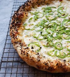 a pizza with cheese and jalapenos sitting on a cooling rack in the oven