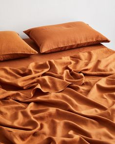 a bed covered in brown sheets and pillows