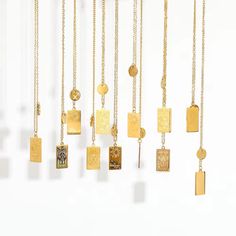 a group of gold necklaces hanging on a white wall next to eachother