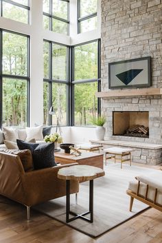 a living room filled with lots of furniture next to large windows on top of a hard wood floor