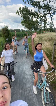 a group of people riding bikes down a road next to grass covered fields and trees