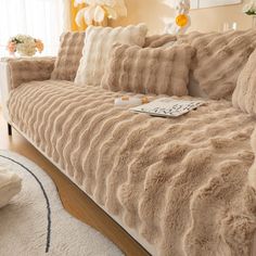 a living room with a couch covered in grey furs and pillows on top of it