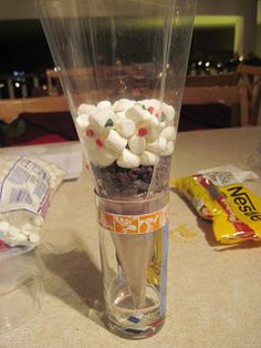 a glass filled with marshmallows sitting on top of a counter next to a bag of candy