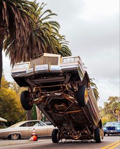 a large truck is being towed down the street by a car and some palm trees