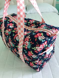 a floral bag with pink and white gingham ribbon hanging from it's side