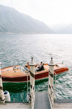 two people in a motorboat on the water next to some steps and railings