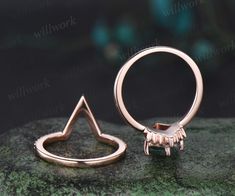 an open ring sitting on top of a mossy rock next to a small triangle