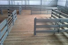 the inside of a building with several metal stalls and railings on top of wooden flooring