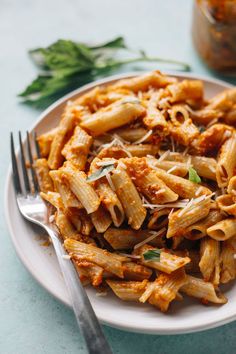 pasta with sauce and parmesan cheese on a white plate next to a fork