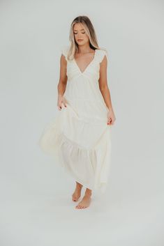 The Katy Midi has so many gorgeous details, it's easy to see why this is one of Worth Collective's new favorite summer dresses. Pictures don't do this beauty justice - from its pleated empire-waist bodice, to its ruffled cap sleeves and ultra-feminine tiered skirt, this dress speaks wildflowers and walks on the beach. Pair with neutral sandals for charming elegance. FIT: Runs true to size. MODEL: Model is 5’7” / wearing a small. MATERIAL: Self: 49% Rayon, 30% Nylon, 21% Tencel. GARMENT DETAILS: Sleeveless, lightweight summer dress in a midi length. Features a plunging V-neckline, with ruffled cap sleeves, pleated bodice, and stretchy, smocked back panel. Dress is constructed with an inverted empire waist, with a full, multi-tiered skirt. Partially lined. SIZE GUIDE: S (2-4) / M (6-8) / L ( Dresses Pictures, Neutral Sandals, Walks On The Beach, Garment Details, Ultra Feminine, Pleated Bodice, Beach Walk, Tiered Skirt, Empire Waist