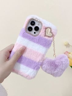 a person holding up a pink and white phone case with a heart charm on it