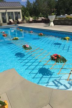 an empty swimming pool with flowers on the side and ladders in the middle for decoration